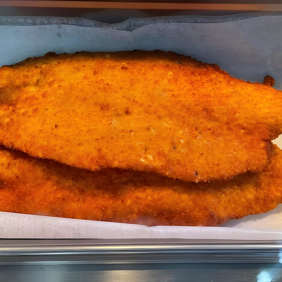 Two crispy, golden-orange breaded cutlets in a metal serving tray.