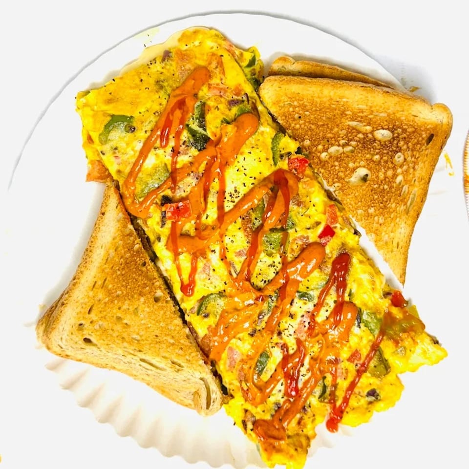 A vibrant omelet with bell peppers and ketchup drizzle, served with two slices of toast.