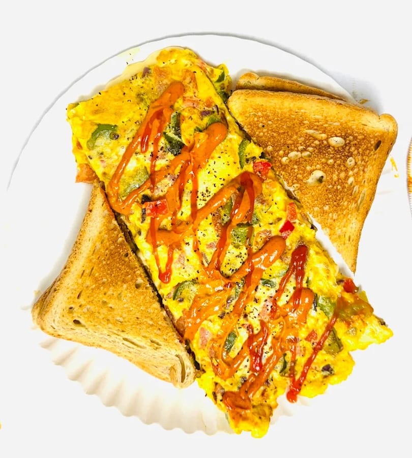A vibrant omelet with bell peppers and ketchup drizzle, served with two slices of toast.